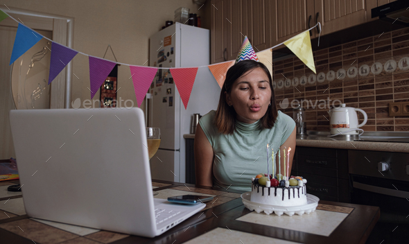 Woman blowing out the candle on the birthday cake and making video call.