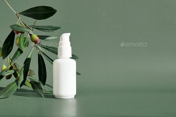 Cosmetic bottle with pump near olive branch on pastel green background