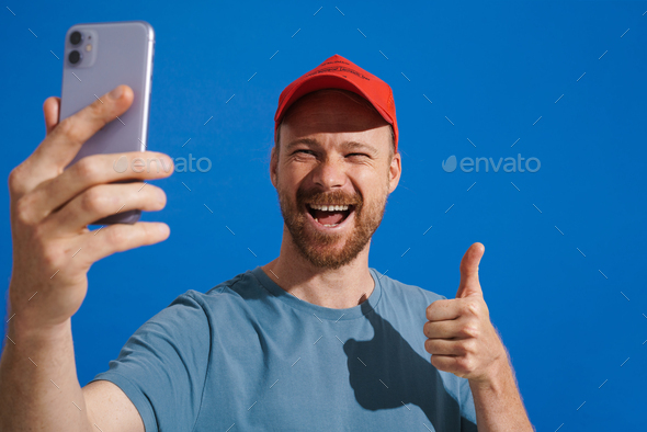 White Ginger Man Wearing Cap Gesturing While Taking Selfie On Cellphone