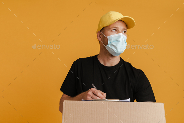 White delivery man in face mask writing down notes on clipboard