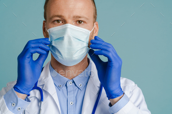 White male doctor posing in face mask and medical gloves