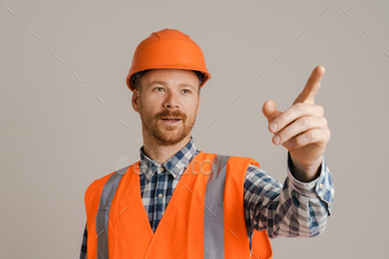 White man worker wearing helmet pointing finger aside