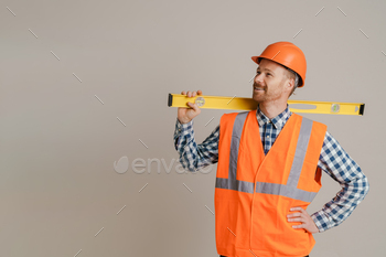 White man worker wearing helmet and vest posing with spirit level tool