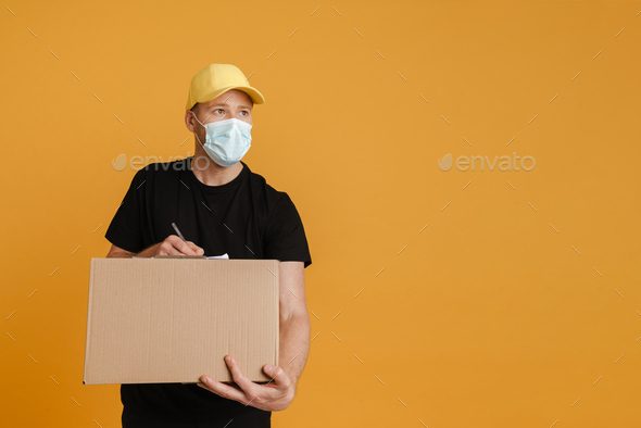 White delivery man in face mask writing down notes on clipboard