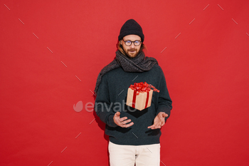White man in warm clothes and eyeglasses posing with gift box