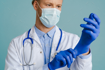 White male doctor in face mask wearing medical gloves