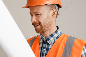 White man worker wearing helmet and vest posing with drawing