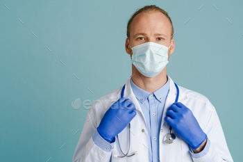 White male doctor wearing face mask posing with stethoscope