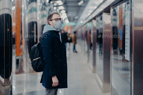man traveler poses on metro station, wears medical mask during coronavirus time - Stock Photo - Images