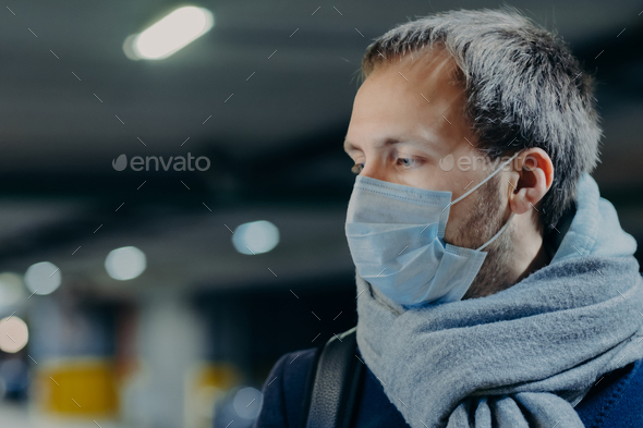 man wears protective mask against new coronavirus from China, wrapped scarf around neck