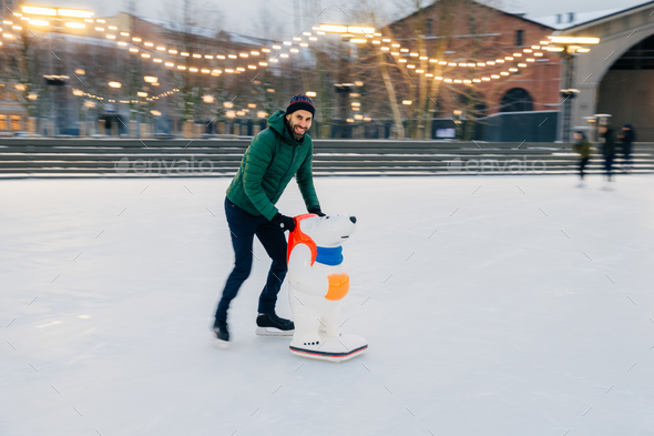 Photo of male skater keeps balance on skate ring, stands on skates with help of skate aid