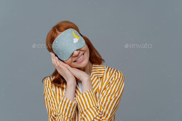 Just relaxing or time for nap. Smiling gentle woman with eye mask, tilts head on pressed palms
