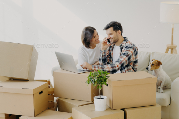 Happy husband and wife move in new bought house, buy furniture online, use modern technology