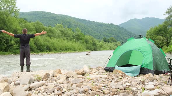 A Tourist Pitched a Green Tent Near a Mountain River alt