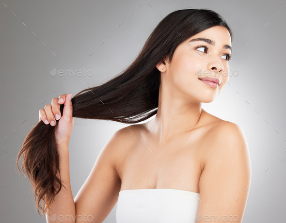 Studio shot of a beautiful young woman showing off her long silky hair against a grey background