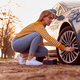 Woman Inflating Car Tyre With Electric Pump On Country Road - PhotoDune Item for Sale