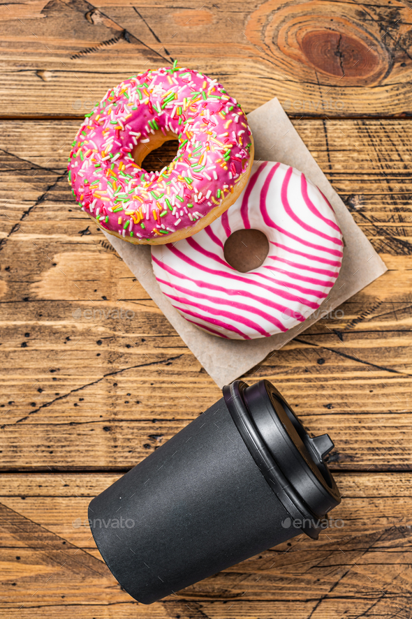 Pink glazed donuts on a kitchen table with coffee. Wooden background. Top view