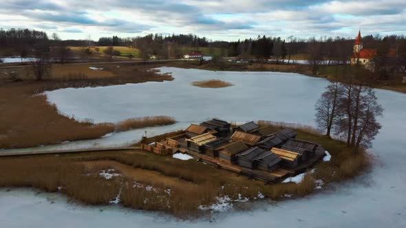 Historical Wooden Buildings on Small Island in the Frozen Lake Araisi in the Winter alt
