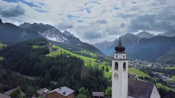 Aerial Flight Over the Bell Tower of a Church in the Dolomites alt