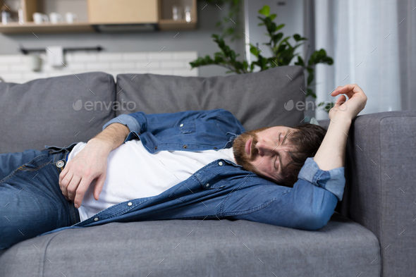 A man at home tired after work sleeps on the couch