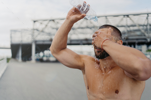 sportsman splashes fresh cold water over head, tries to refresh after hard exercising outdoor