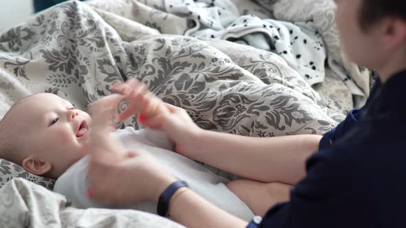 Mother Plays with Her Baby at Home on Her Lap