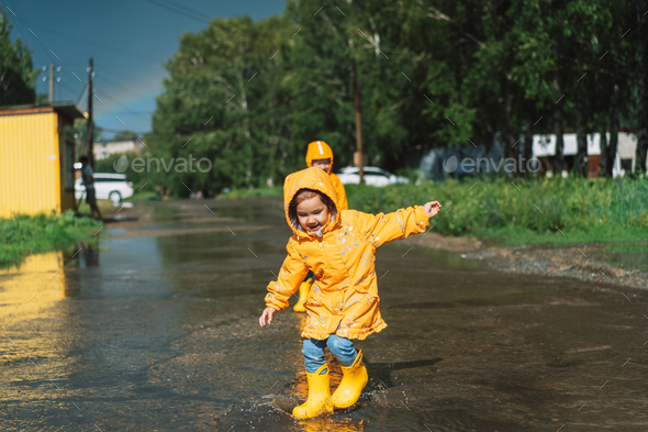 Children in yellow rubber boots run through the puddles
