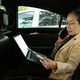 Busy mature businesswoman having phone conversation and using laptop on backseat. - PhotoDune Item for Sale