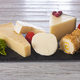 Slices of assorted French, Spanish and Italian cheese on a dark board, served with fruit - PhotoDune Item for Sale