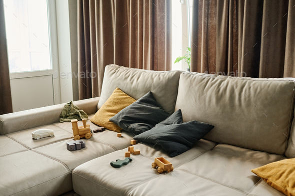 Wide leather couch of delicate grey color with large and small pillows  Stock Photo by Pressmaster