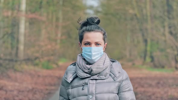 Woman Turns Around and Removes the Protective Mask From Face and Smiles alt