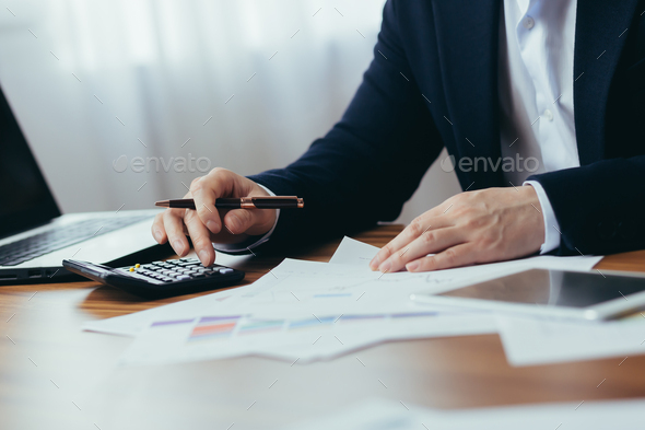 Close-up photo, businessman accountant\'s hand counts on a calculator