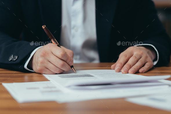 Close-up photo of Asian businessman\'s hands signing bank documents