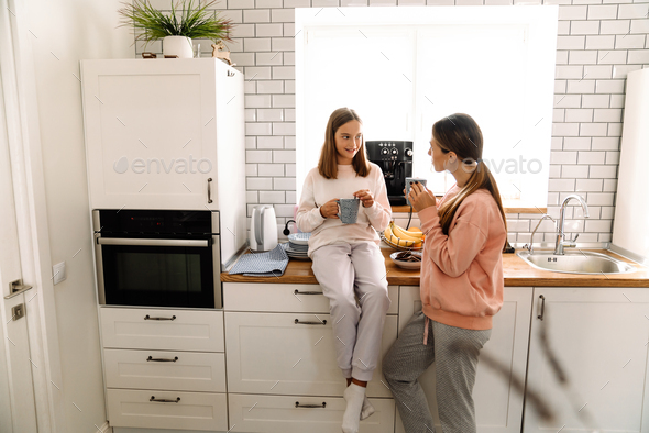 White mother and daughter talking and drinking tea in kitchen Stock ...