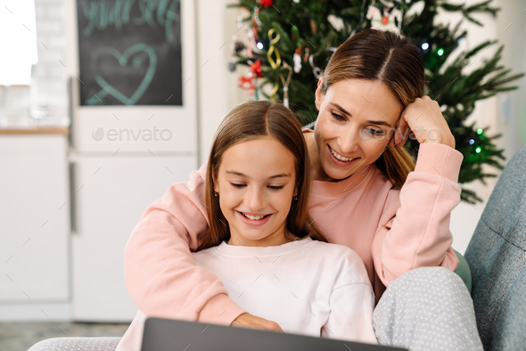 White mother and daughter using laptop together while sitting on sofa - Stock Photo - Images