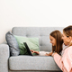 White mother and daughter using laptop together on sofa - PhotoDune Item for Sale