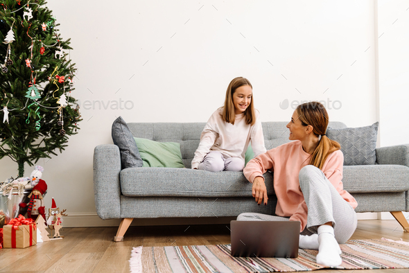 White mother and daughter smiling and using laptop at home - Stock Photo - Images