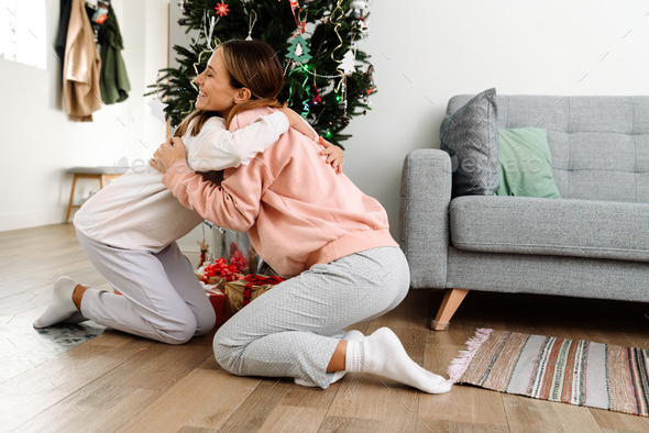White mother and daughter hugging while decorating christmas tree - Stock Photo - Images