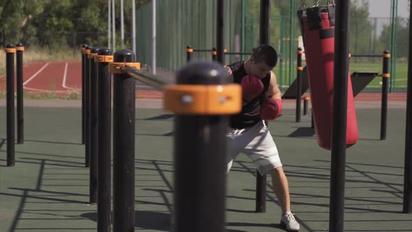 Man Boxing Punching Bag At Sports Ground Outdoors alt