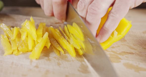 Slow motion close up of a chef knife slicing a yellow bell pepper alt