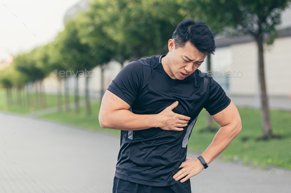 Male asian athlete, has chest pain fitness in the park and running, heart aches after