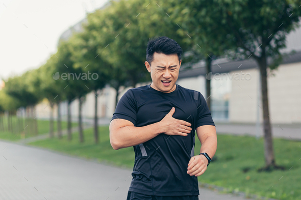 Male asian athlete, has chest pain fitness in the park and running, heart aches after