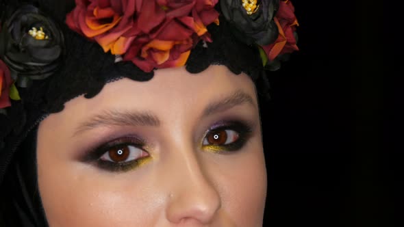 Professional Girl Model with Beautiful Makeup Poses in a Black Cap and Wreath on Her Head in Front