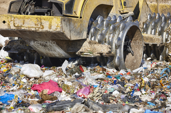 Heavy machinery shredding garbage in an open air landfill. Waste - Stock Photo - Images