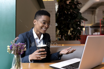 Happy woman sitting in a cafe with a hot drink makes an online meeting, video call