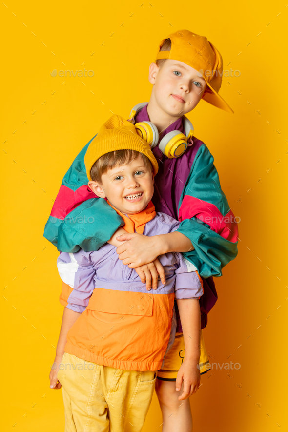Two kids in stylish vintage 80s clothes have a fun on yellow background  Stock Photo by Masson-Simon