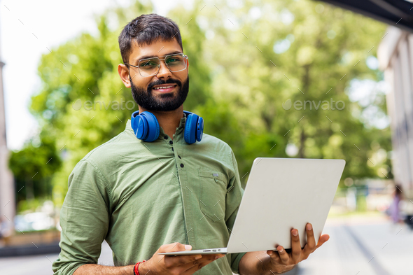 Portrait Indian student programmer using laptop computer in park