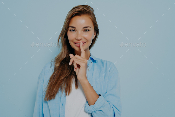 Pretty female placing fingers on lips making sign symbol