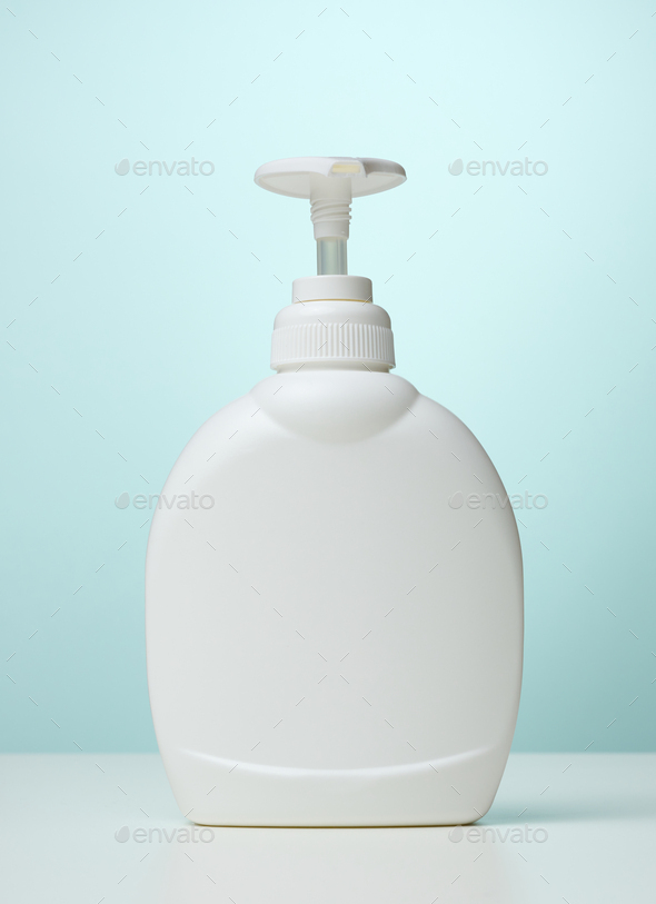 White plastic container with a pump for cosmetic liquid, liquid soap on the table