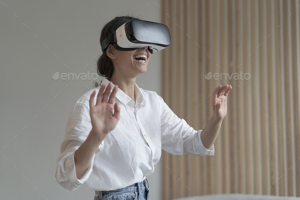 Impressed amazed female office worker using VR glasses while working in augmented reality world